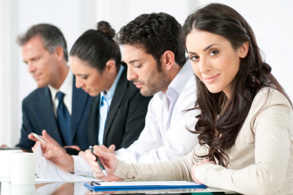 Satisfied,Smiling,Business,Woman,Looking,At,Camera,With,Working,Colleagues